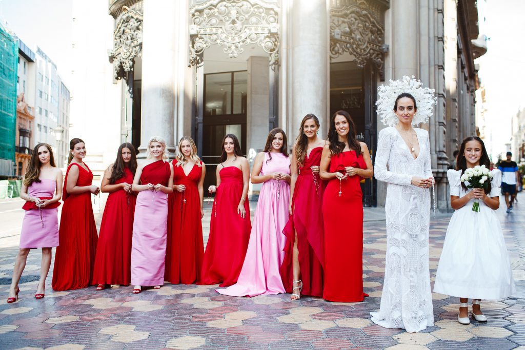 Image depicts a bride in custom gown with her bridal party